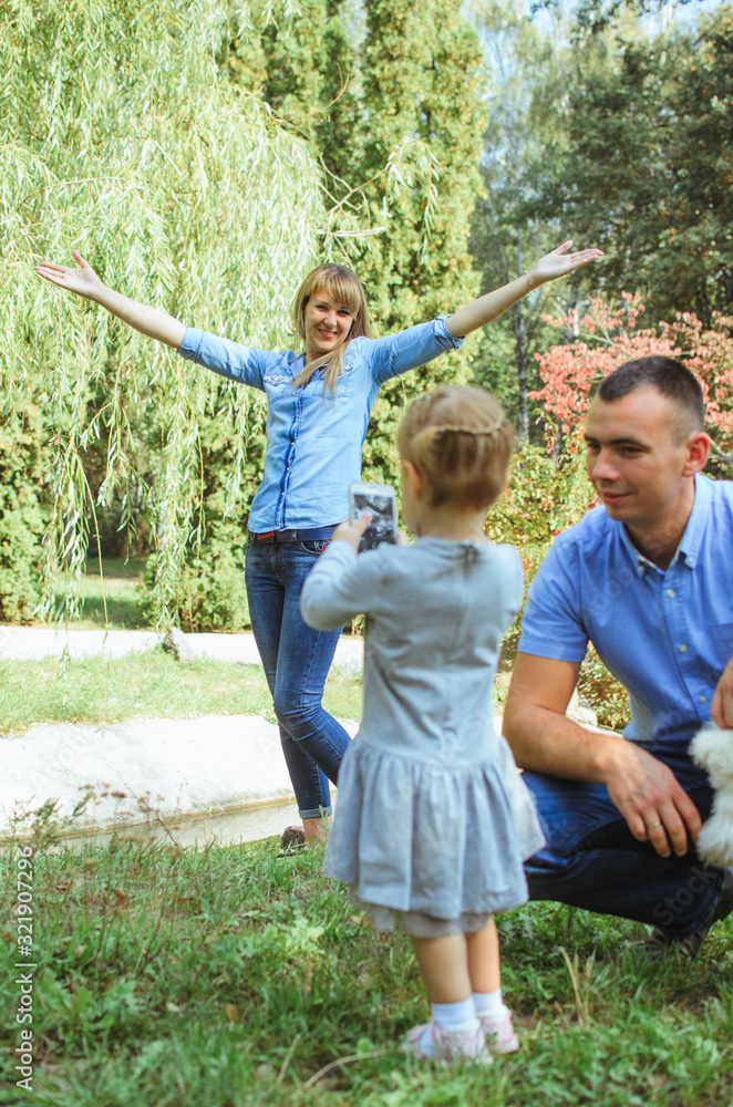 Obraz premium family shot in the park, summer day. mom, dad, daughter have fun day off. Mom and Dad are wearing a denim suit. smart girl