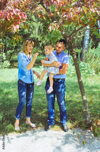 family shot in the park, summer day. mom, dad, daughter have fun day off. Mom and Dad are wearing a denim suit. smart girl