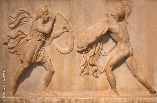 Ancient Greek bas-relief - Amazon with full military equipment fighting a Greek warrior. Athens, Greece photo