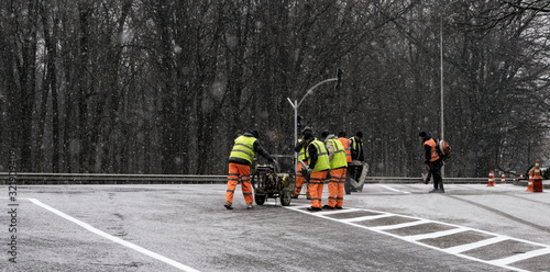 A group of repairmen performs repairs on a section of the road in winter