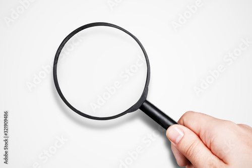 female hand holding magnifier over gray background, mock-up image