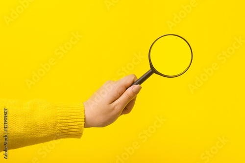 magnifier in hand  over yellow background
