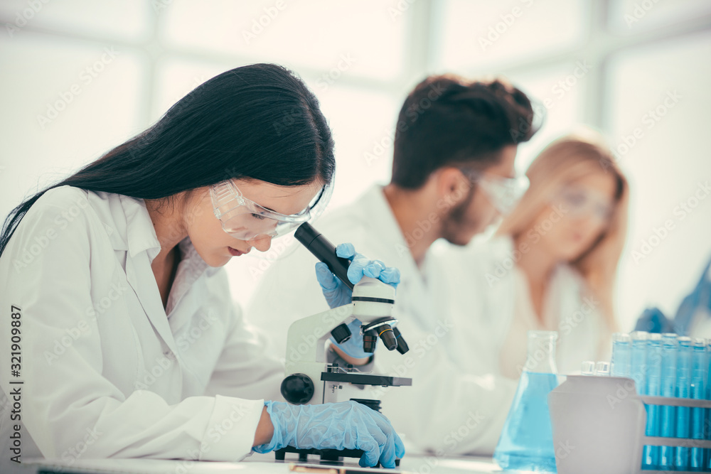 female doctor using a microscope to check for a coronavirus test female doctor using a microscope to check for a coronavirus test