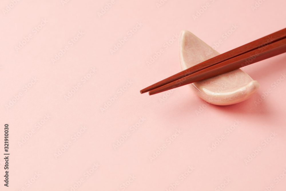 Wooden chopsticks and chopstick rest on bright paper background. Close up. Copy space. Wooden chopsticks and chopstick rest on bright paper background. Close up. Copy space.