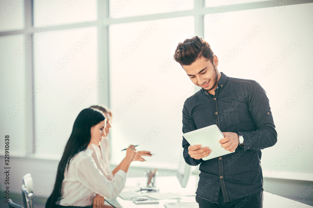 young businessman with digital tablet standing in office. young businessman with digital tablet standing in office.
