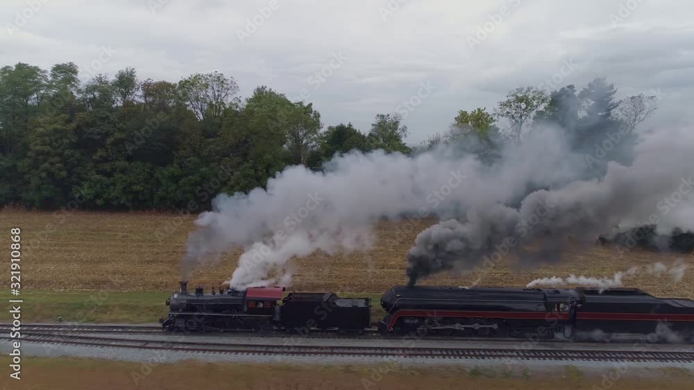 Aerial Side View of a Two Steam Locomotives Double Heading a Freight Train Puffing Along with Black Smoke and Steam Aerial Side View of a Two Steam Locomotives Double Heading a Freight Train Puffing Along with Black Smoke and Steam