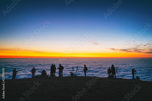 photographers tourists high in the mountains take pictures of the rising sun above the clouds