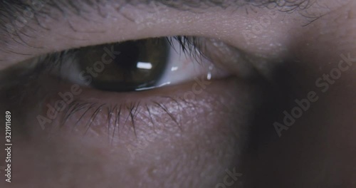 Macro shot of a male eye as he opens his eyes and stares deeply into the soul of the viewer while his pupils constrict in the light.