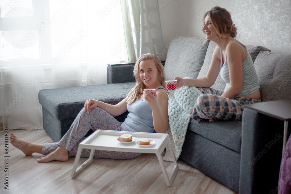 Two friends have breakfast together at the morning in the home room. Women wearing pajamass and hold the cup of tea with cookies. People relaxing in the weekend Two friends have breakfast together at the morning in the home room. Women wearing pajamass and hold the cup of tea with cookies. People relaxing in the weekend