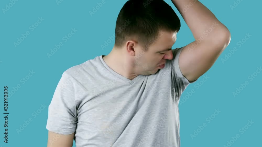 Young man sniffing his armpit, something stinks very bad. Bad smells concept. Young man sniffing his armpit, something stinks very bad. Bad smells concept.