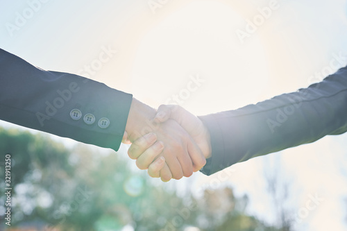 backlitted business women handshake on a blurry outdoor background