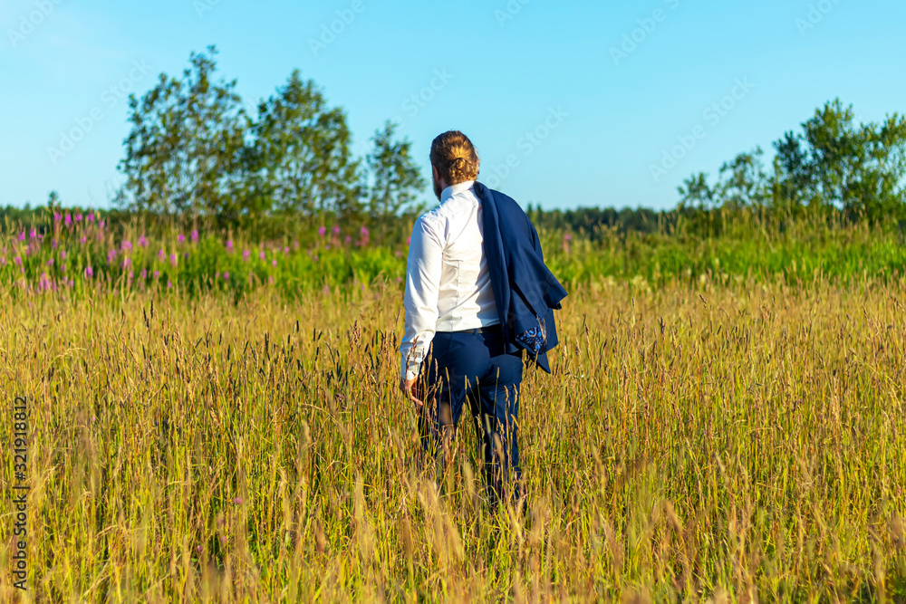 Caucasian man in a suit is walking on the field. Concept businessman in nature. Caucasian man in a suit is walking on the field. Concept businessman in nature.