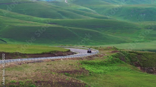 One Black SUV car driving on asphalt winding empty serpentene and famous Caucasus Dzhily Su road at summer sunny day - Aerial drone view photo