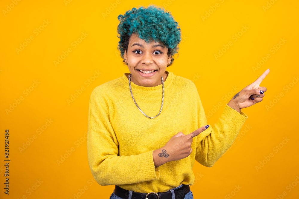 fashionable african american girl or woman with blue hair isolated on yellow background