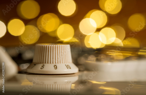 Macro of a white electric guitar volume knob on 9 with abstract bokeh lights in the background. Side view, flat.