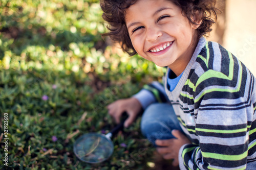 A kid boy looking through magnifier at plants. Children, discovery and botany concept