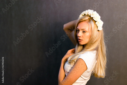 Beautiful blonde girl in the studio. With a wreath on his head.
