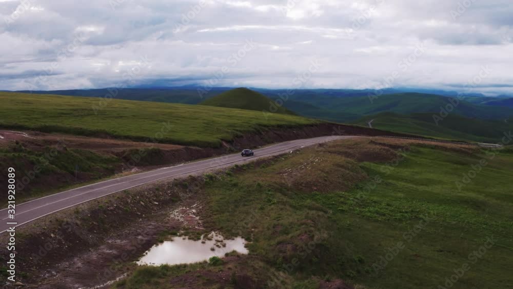 One black sedan car driving on asphalt winding empty serpentene and famous Caucasus Dzhily Su road at summer sunny day - Aerial drone view One black sedan car driving on asphalt winding empty serpentene and famous Caucasus Dzhily Su road at summer sunny day - Aerial drone view
