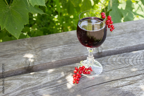 Glass of red wine with red currants on nature, wine making concept