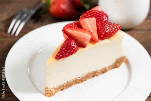 Cheesecake slice with strawberries. Plain classical New York cheesecake decorated with fresh strawberry slices. Tasty dessert