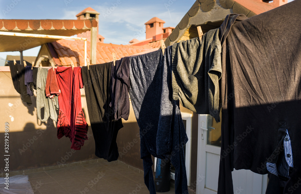 Clothes hanging with wooden pegs to clothes line. Lots of clothes on blue sky background.