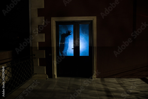 The silhouette of a human in front of a window at night. Scary scene halloween concept of blurred silhouette of maniac.