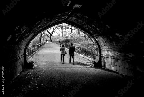 Silllhouette Couple Walking Udner Bridge through Central Park New York