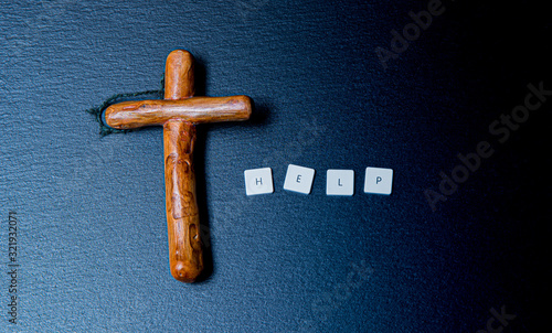 Wooden Christian cross on a dark background with the inscription help. © Michal Lech