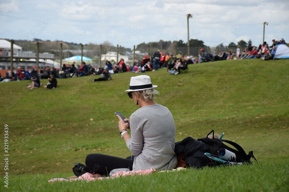 A woman checks her mobile phone at a motor racing event A woman checks her mobile phone at a motor racing event