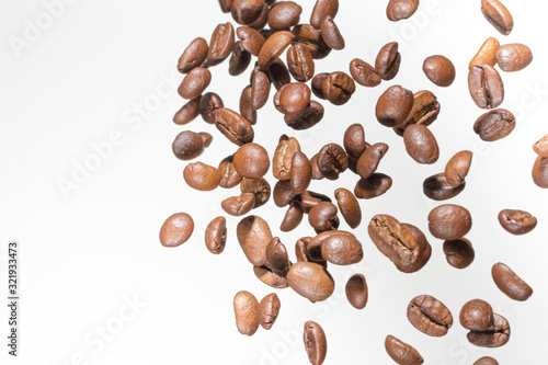 Falling coffee beans, in motion, on a white background. Selective focus.