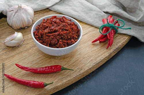 Fototapeta Naklejka Na Ścianę i Meble -  Spicy chili on a dark background in ceramic plates on a wooden Board, flatlay. Used as an ingredient for harissa, ajika, muhammara. East and middle East kitchen.