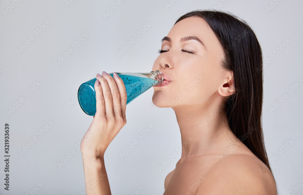 A close-up, Sensual Asian woman drinks detox cocktail after spa treatments. A close-up, Sensual Asian woman drinks detox cocktail after spa treatments.