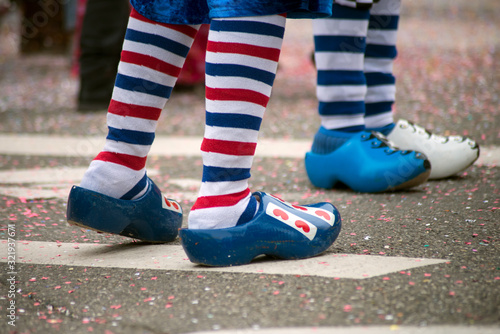 Billede på lærred Closeup of legs of people parading in the street with blue wooden shoes and stri
