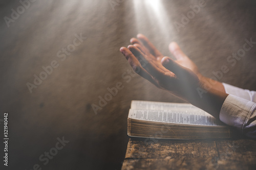 Hands folded in prayer on a Holy Bible in church concept for faith photo