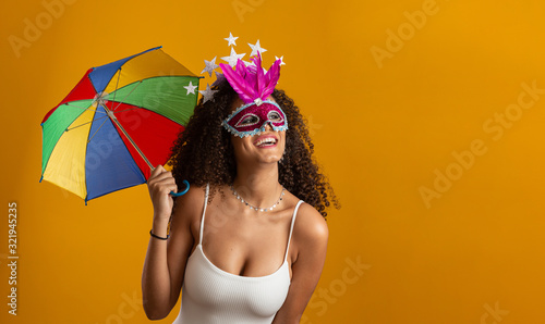 Young curly hair woman celebrating the Brazilian carnival party with Frevo umbrella on yellow. photo