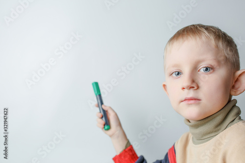 child with marker in his hand points on blackboard
