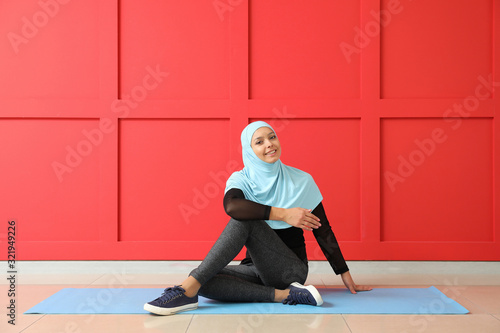 Canvas Print Sporty Muslim woman practicing yoga near color wall