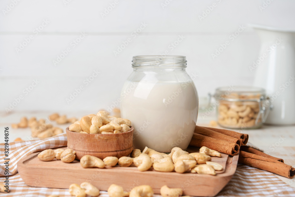 Jar of cashew milk with nuts on wooden table Jar of cashew milk with nuts on wooden table