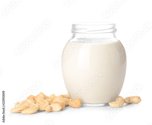 Jar of cashew milk with nuts on white background