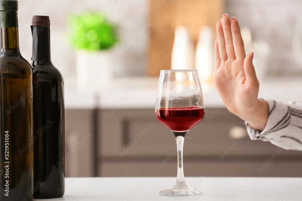 Woman refusing to drink wine at home. Concept of alcoholism Woman refusing to drink wine at home. Concept of alcoholism