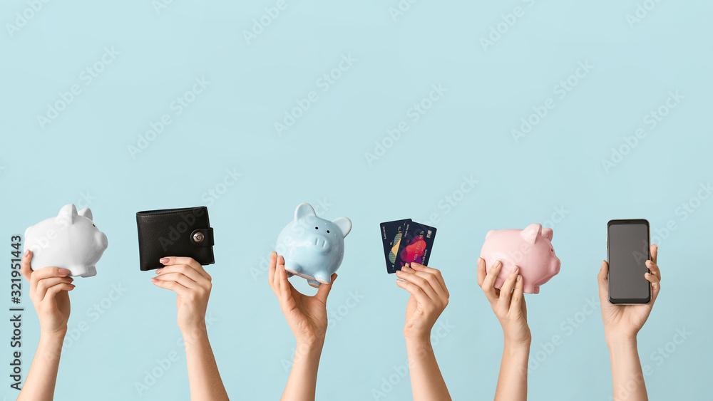Female hands with piggy banks, credit cards, wallet and mobile phone on color background. Concept of online banking - obrazy, fototapety, plakaty 