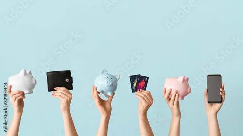 Female hands with piggy banks, credit cards, wallet and mobile phone on color background. Concept of online banking