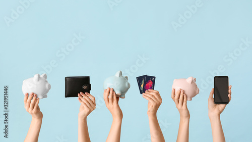 Female hands with piggy banks, credit cards, wallet and mobile phone on color background. Concept of online banking photo