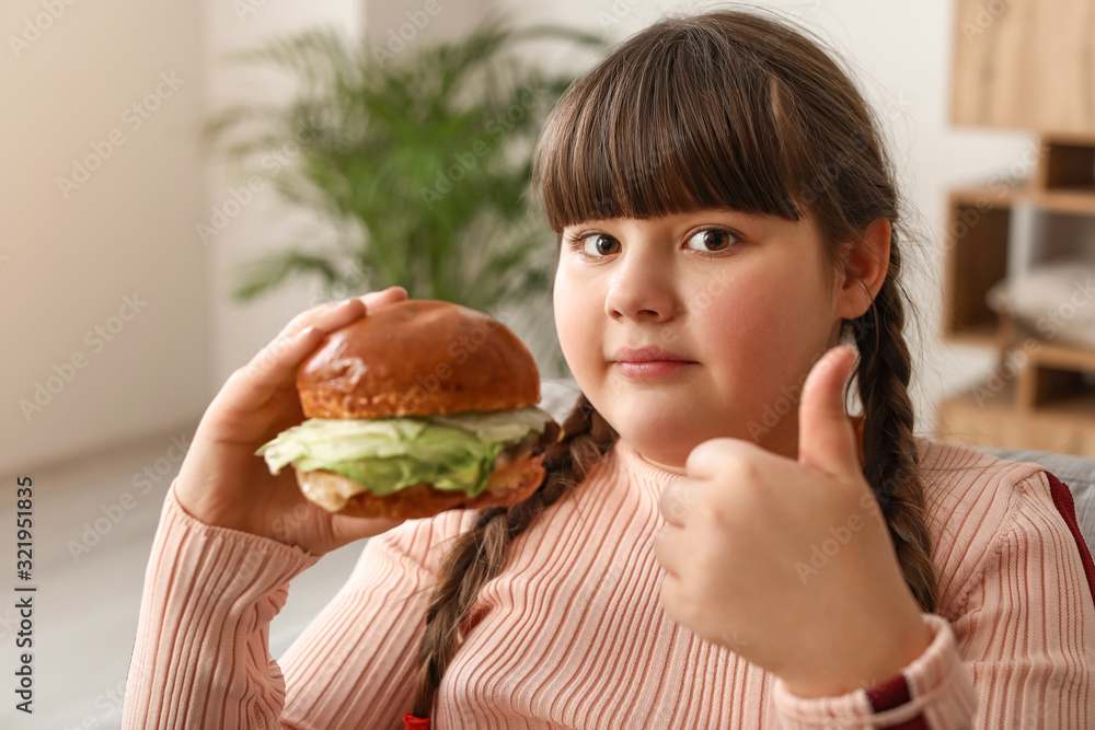Overweight girl eating unhealthy burger at home Overweight girl eating unhealthy burger at home