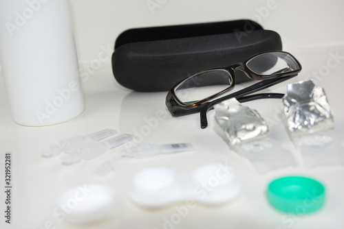 Variety of eye care products against white background. Glasses, contacts, eye drops, and more. Flat lay products