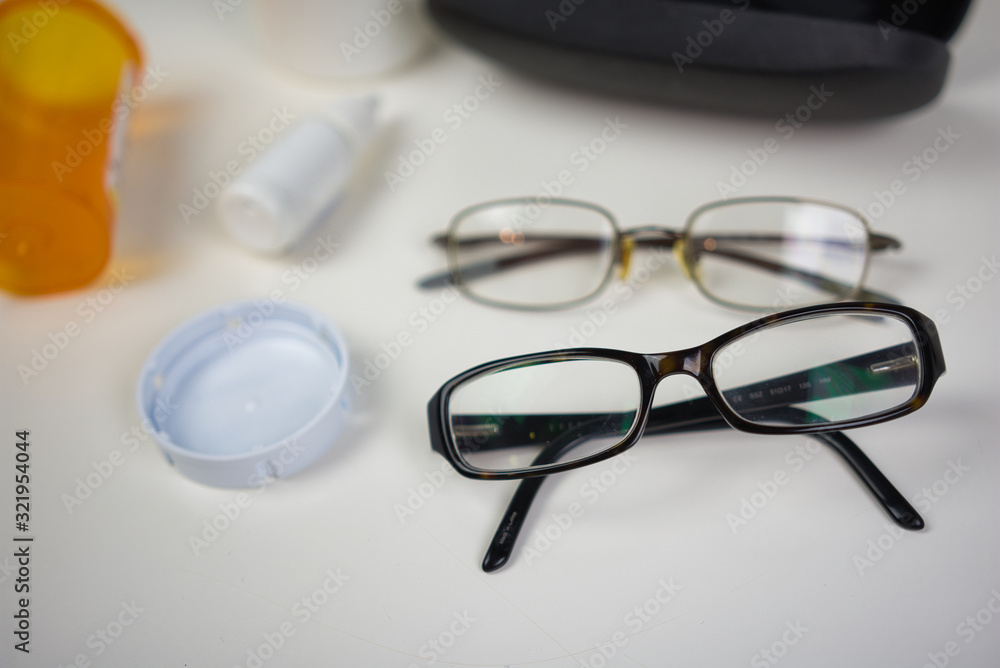 Glasses on white counter with various eye care products. Flat lay of medical supplies for vision care Glasses on white counter with various eye care products. Flat lay of medical supplies for vision care