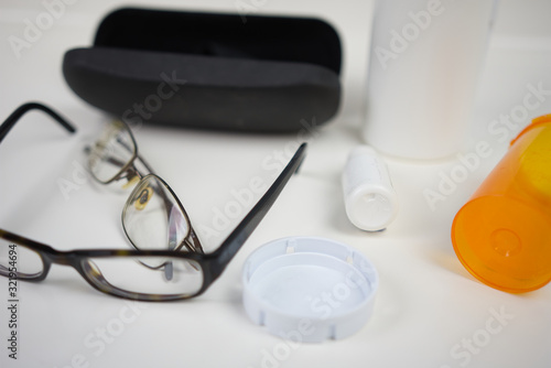 Glasses on white counter with various eye care products. Flat lay of medical supplies for vision care