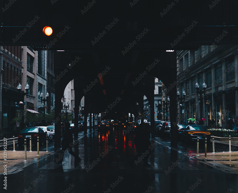 people silhouetted underneath a bridge on a rainy day