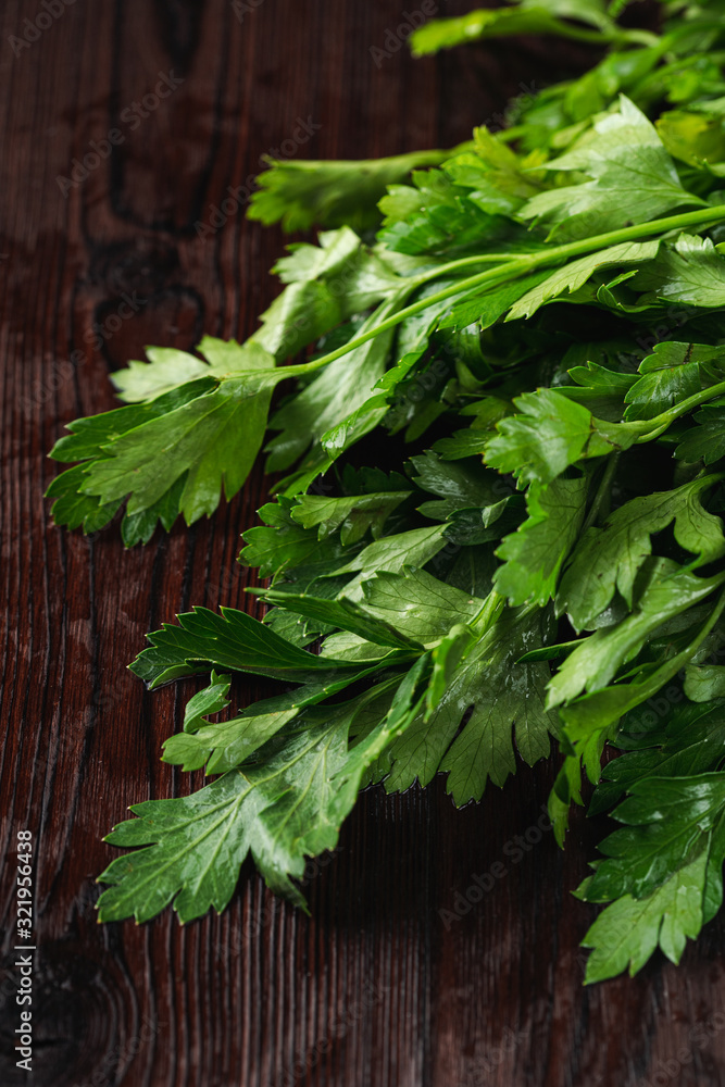 Bundle of fresh raw parsley on dark wooden table close up Bundle of fresh raw parsley on dark wooden table close up