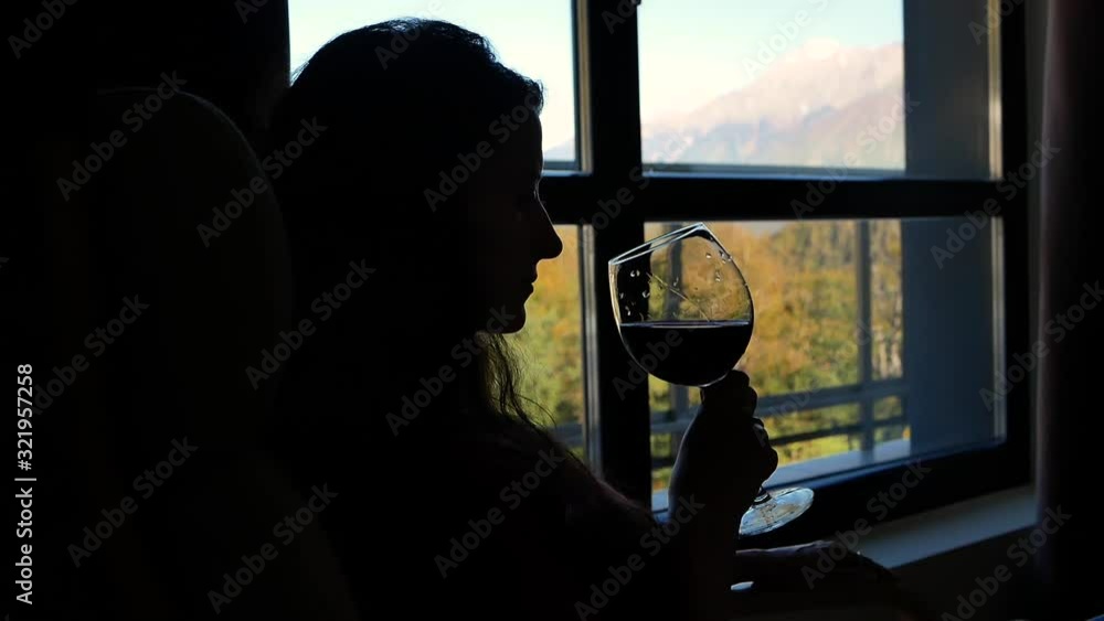 Silhouette of woman with glass of wine in hand. concept of relaxation and tranquility Silhouette of woman with glass of wine in hand. concept of relaxation and tranquility